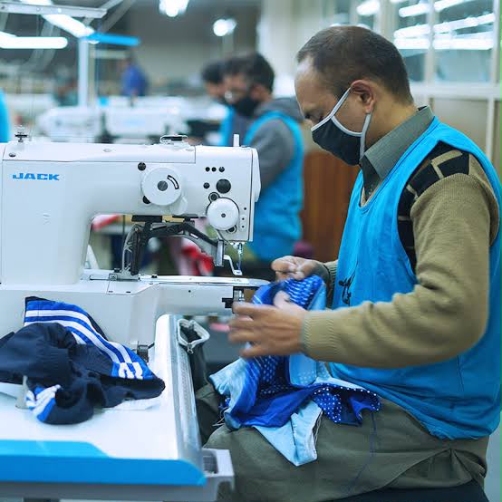 Operator sewing blue sportswear on an industrial machine